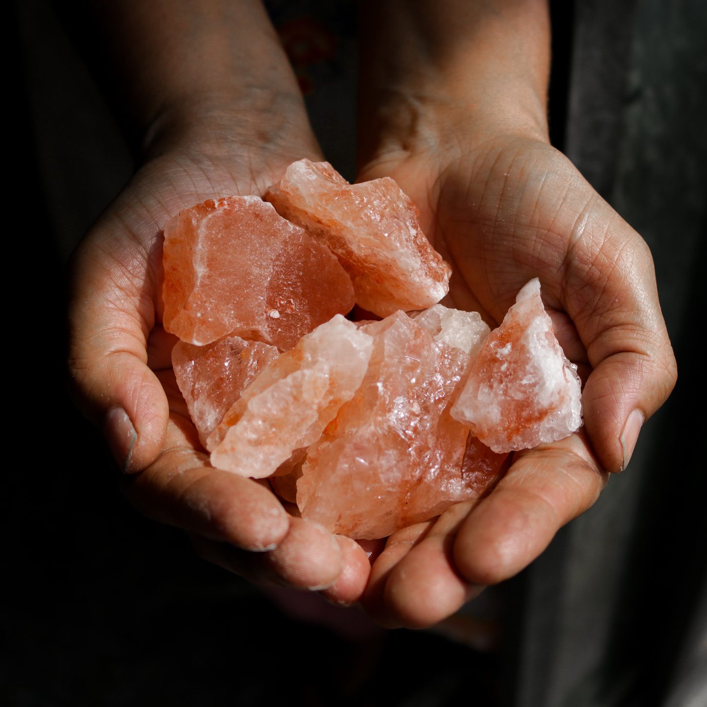 Pink himalayan salt pieces holding in hands.